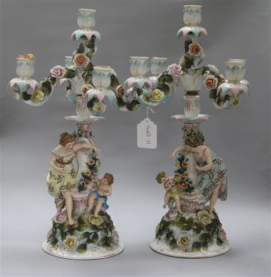 A pair of Sitzendorf figural and flower-encrusted four-branch five-light candelabra